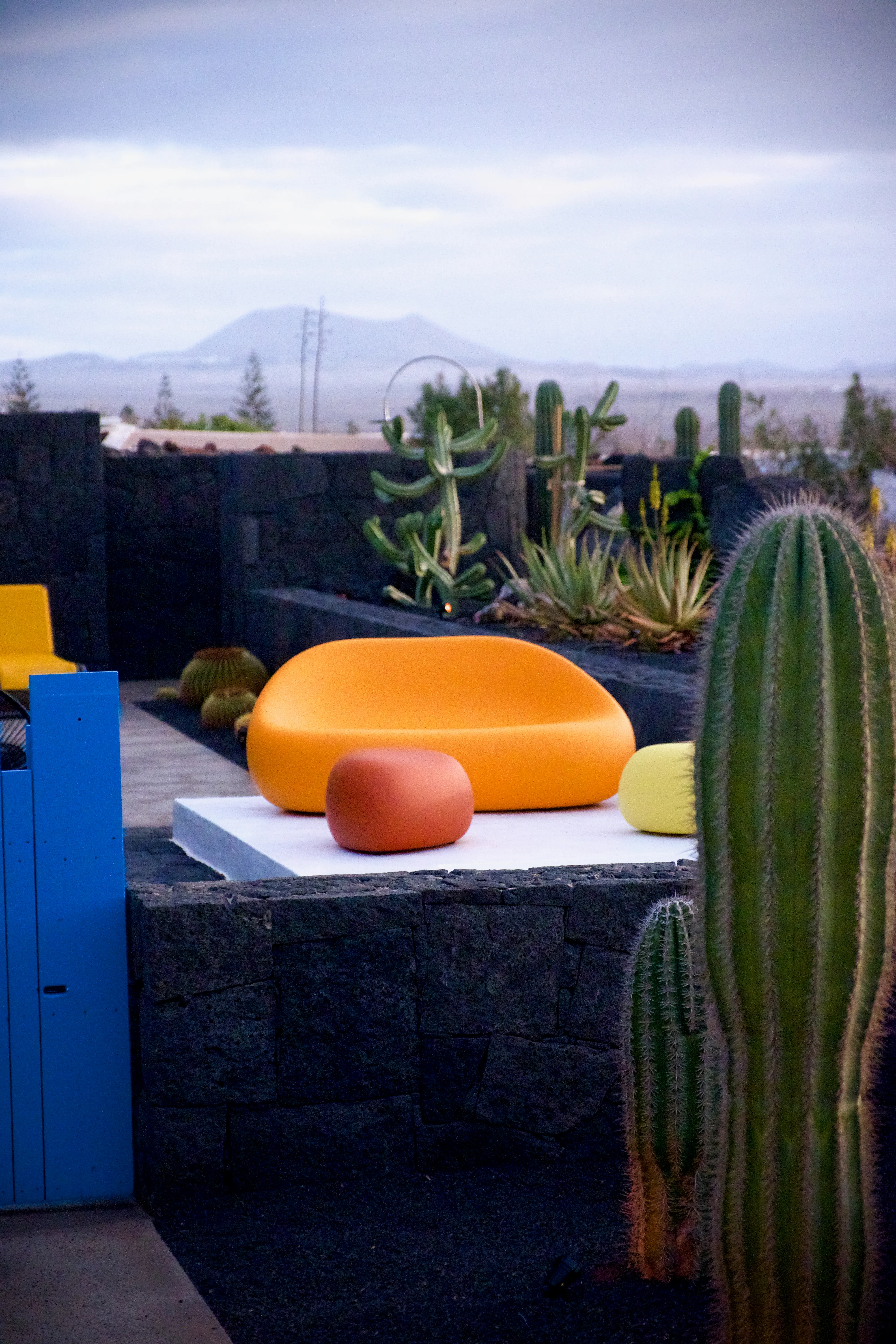Orange lounge chair and cactus in the garden, cliffs behind
